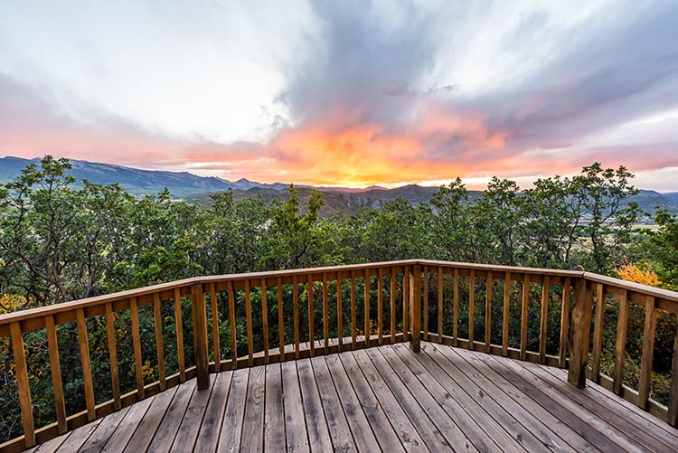 A wooden deck surrounded by trees at sunset