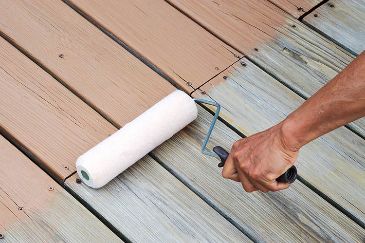 A person painting a deck