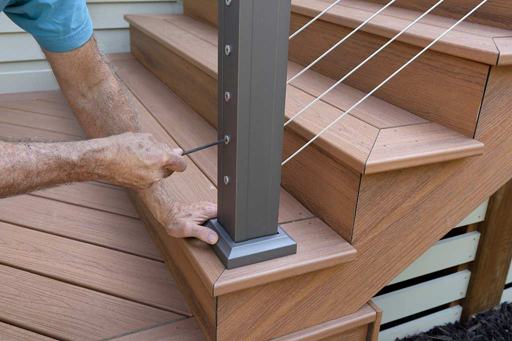A man installing a deck railing