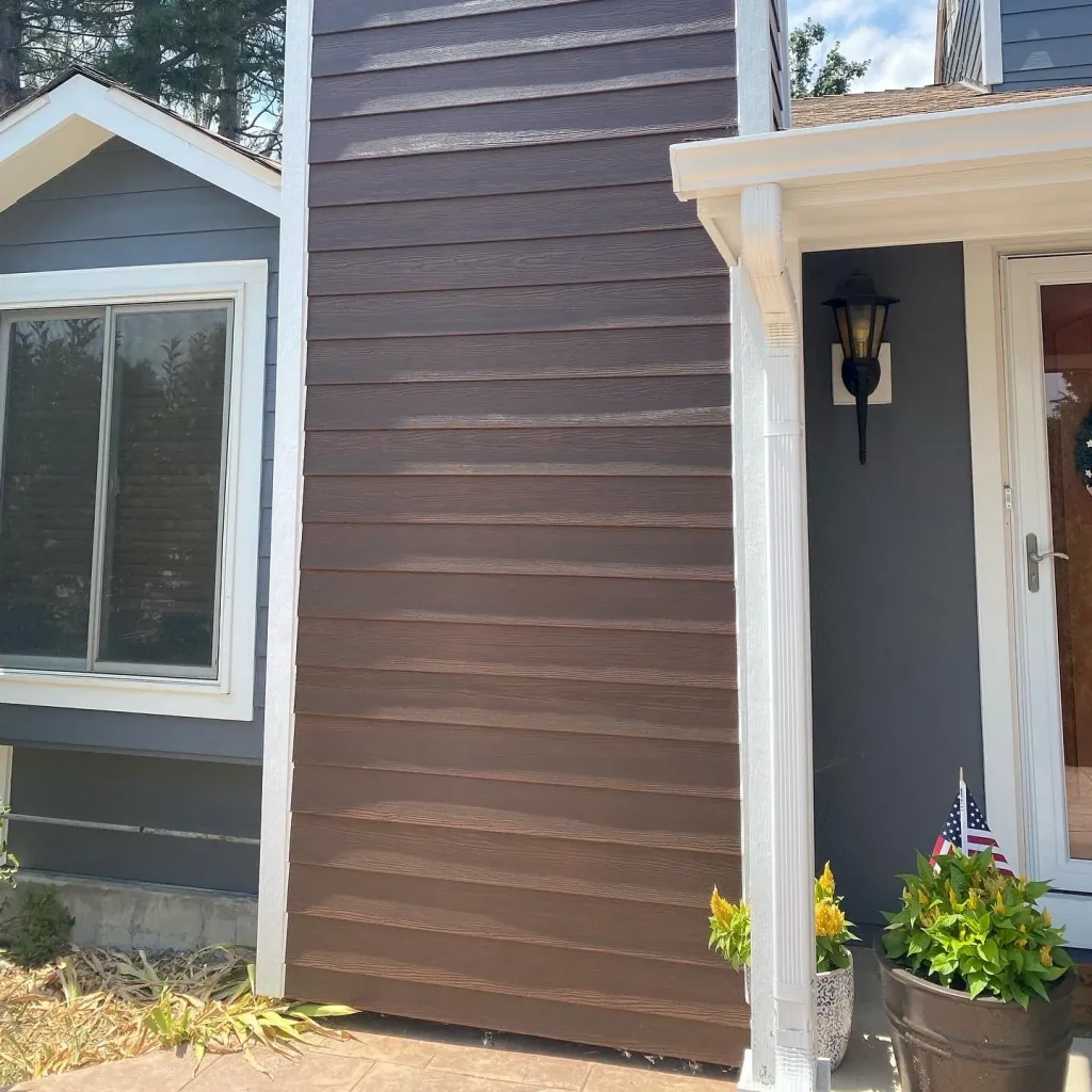 Person painting wood house exterior