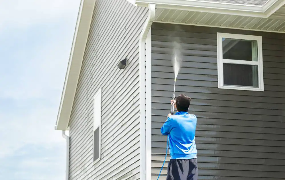 A man cleaning exterior house siding.