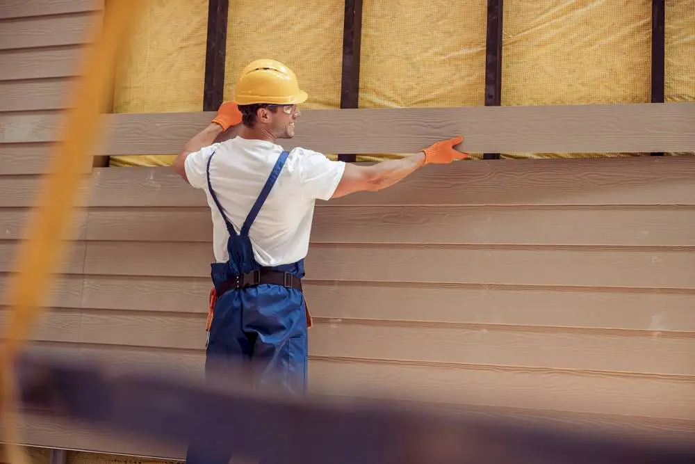 A happy worker installing house siding.