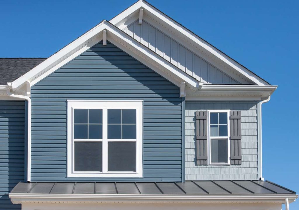 A house with dark gray horizontal vinyl siding and white accents.