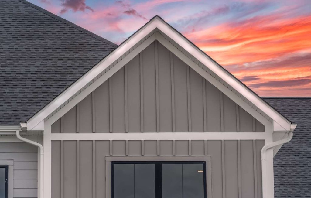 A house with dark gray horizontal vinyl siding and white accents.