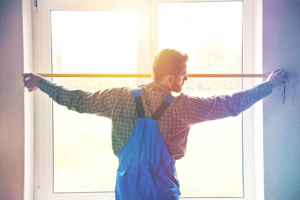 A worker measuring a home window.