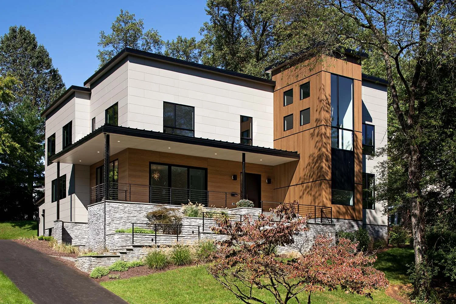 Modern two-story house with white siding on top, wood-toned siding below and on a side tower, plus a stone retaining wall with cable railing out front. Caption below describes LP SmartSide engineered wood siding — rot/termite treated, 5/50 warranty with hail coverage to 1.75", combustible.